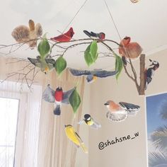 a bird mobile hanging from the ceiling in a living room with curtains and paintings on the walls