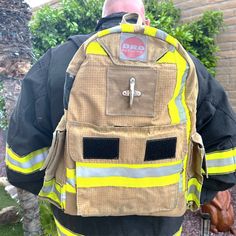 a fireman with his back to the camera, wearing a backpack that has reflective patches on it