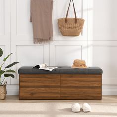 a wooden bench sitting in front of a white wall next to a basket and plant