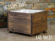 a wooden box sitting on top of a floor next to a brick wall with the words includes pans and rack