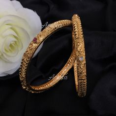 Antique gold-plated bangle from Amrapali is a masterpiece of South Indian jewelry. Known as a Kada bracelet, it features traditional jadau craftsmanship and Kemp stones, making it ideal for temple and bridal wear. This exquisite piece serves as a timeless gift, embodying the rich cultural heritage of India. *𝐏𝐑𝐎𝐃𝐔𝐂𝐓 𝐃𝐄𝐓𝐀𝐈𝐋* * Material: Brass * Plating: Gold Plated *𝐃𝐈𝐌𝐄𝐍𝐒𝐈𝐎𝐍𝐒* * Weight: 15 gm * Width: 0.2 Inches     *𝐃𝐈𝐒𝐂𝐋𝐀𝐈𝐌𝐄𝐑* Product color may slightly vary du 4 Gold Bangles Design, Gold Plated Bangle Bracelets For Marriage, Traditional Gold Plated Bracelets For Wedding, Traditional Gold Plated Wedding Bracelet, Gold Plated Temple Jewelry Bangle As Gift, Temple Jewelry Style Gold Plated Bangle Gift, Traditional Bracelets With Intricate Design For Marriage, Traditional Bracelet With Intricate Design For Marriage, Intricate Design Bangle Bracelet For Marriage