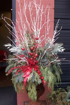 a potted plant with red berries and greenery in front of a brick wall