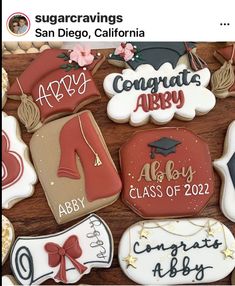 cookies decorated with graduation caps, gowns and shoes are displayed on a wooden table