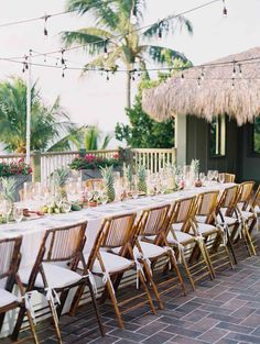 a long table is set up with white linens and wooden chairs