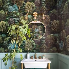 a bathroom with green wallpaper and a white sink in front of a round mirror