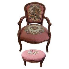 a pink chair and footstool with a floral design on the back, sitting next to each other