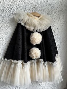 a black and white dress hanging on a wall with two pom poms attached to it