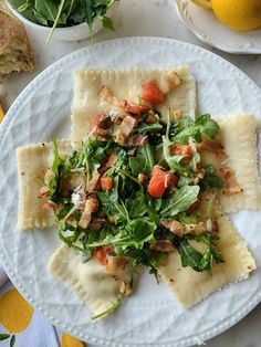 a white plate topped with ravioli covered in veggies