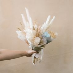 a person holding a bouquet of flowers in their left hand and the other hand is reaching for it