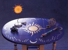 a table with an artistically painted sun and moon design on it, surrounded by other items