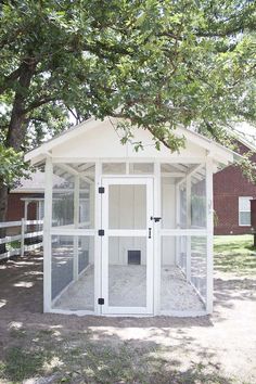 a small white outhouse sitting under a tree