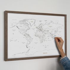 a person is pointing to a map on the wall in front of their head and hand