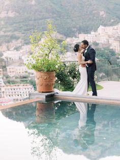 a bride and groom standing next to a pool