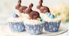 three cupcakes decorated with chocolate bunny bunnies on a white cake platter