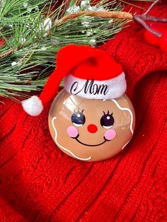 a christmas ornament with a santa hat on it's head sitting next to a pine tree