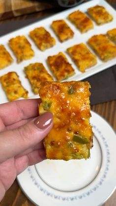 a person holding up a piece of food on a plate with other foods in the background