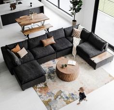 a living room filled with furniture and a baby standing in front of the sectional couch