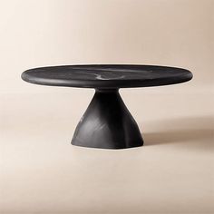 a round table with black marble top on a beige background in the shape of an egg