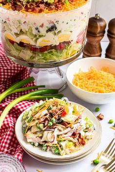 this layered salad is loaded with lots of vegetables and meats, along with other side dishes