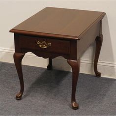 a small wooden table sitting on top of a carpeted floor next to a wall