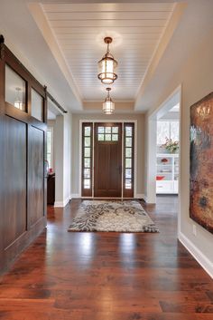 an entry way with wood floors and large painting on the wall, along with two doors leading to another room