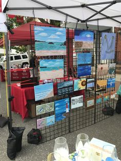 an outdoor market with paintings and wine glasses