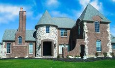 a large brick house sitting on top of a green grass covered field in front of a blue sky