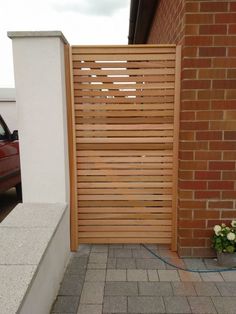 a wooden gate on the side of a brick building next to a flower pot with flowers in it