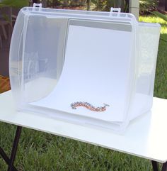 a plastic box sitting on top of a table with a snake in it's side