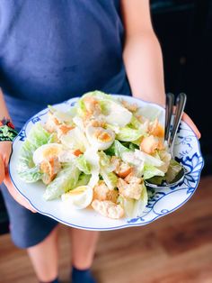 a person holding a plate with salad on it