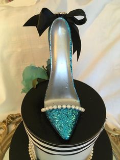 there is a shoe cake on top of a plate with pearls and blue glitters