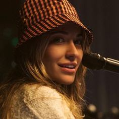 a woman wearing a hat and singing into a microphone