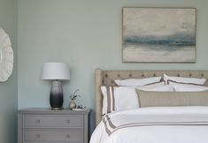 a bedroom with a bed, nightstand and painting on the wall