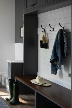 a coat rack and hat on a bench in a room with gray walls, wood flooring and white tiles