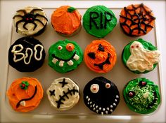 twelve decorated cupcakes in the shape of pumpkins and ghost faces on a white tray