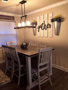 a dining room table with four chairs and two hanging planters on the wall above it