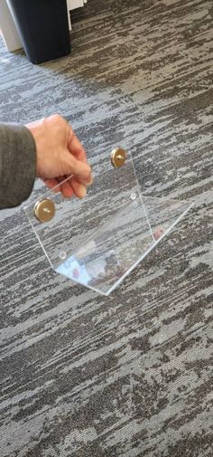 a person holding onto a clear plastic object on the floor in front of a carpeted area