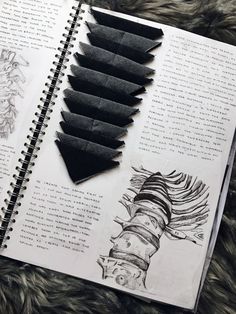 an open book with black paper cut out into shapes and some writing on the page