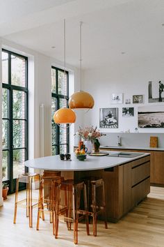 a kitchen with an island and stools in the center, surrounded by large windows