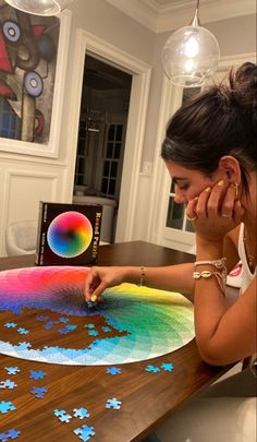 a woman sitting at a table with a piece of puzzle on it's surface