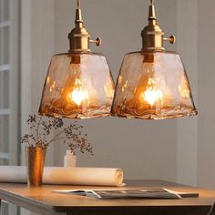 two lights hanging from a ceiling over a table