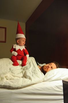 a man laying in bed with a baby on his lap and an elf hat on