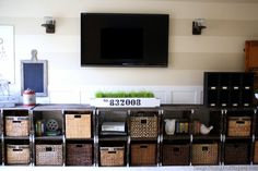 there is a television on the wall above many baskets