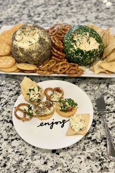 a plate with crackers, cheese balls and pretzels on it