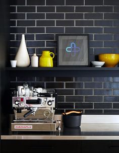 a coffee machine sitting on top of a counter next to a shelf filled with vases