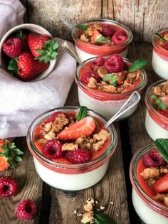 four desserts with strawberries and crumbs in them on a wooden table