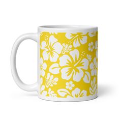 a yellow and white coffee mug with large flowers on it's side, sitting in front of a white background