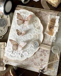 an altered book with buttons and lace on it, surrounded by other items such as ribbons