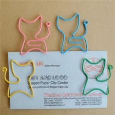 three different colored cat and dog shaped paper clips on top of a piece of paper