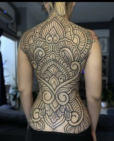 the back of a woman's body is covered in intricate tattoo designs on her upper and lower back